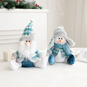 Blue and grey plush Christmas Santa and snowman dolls sitting in a festive home setting