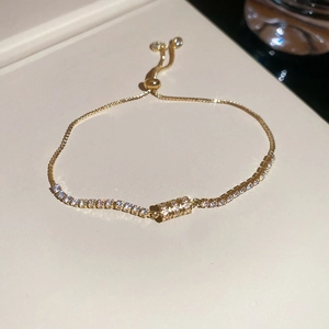 Detail of gold adjustable bracelet with sparkling zircon cylinder charm and slider clasp
