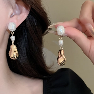 Gros plan sur des boucles d'oreilles perles baroques et pendentifs dorés sur un mannequin