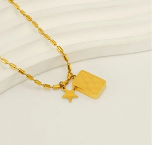 Détail du pendentif carré à damier doré avec étoile sur une chaîne à billes polie