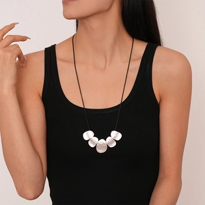 Close-up of minimalist black cord necklace with five irregular silver metal charms on a model