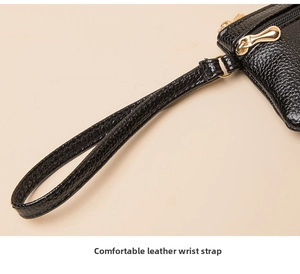 Detail of lychee pattern leather wrist strap with gold metal buckle on black coin purse