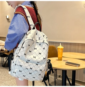 Close-up of white quilted school backpack with cute black bows and ribbon accents