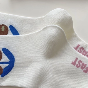 Detail of white cotton crew socks with fruit pattern and pink FAST printed lettering