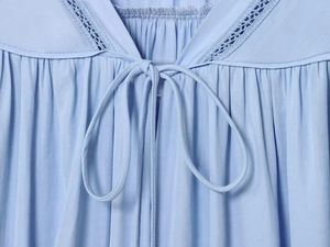 Detail van een lichtblauwe blouse met kanten randen en een verfijnde strik bij de nek