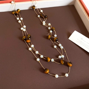 Nahaufnahme von Tigerauge-Perlen und Perlen auf einer eleganten lagen-Halskette