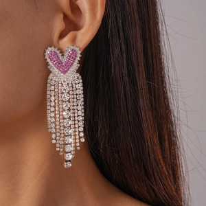 Vue détaillée de boucles d'oreilles cœur avec strass roses et longs pompons