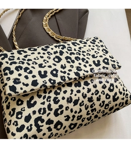 Detail of leopard print canvas bag with golden chain strap on grey blazer