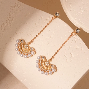 Detailed shot of gold long tassel earrings with white pearls and sparkling rhinestones
