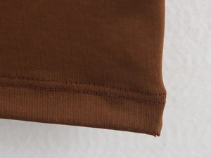 Detail view of double-stitched hem on brown knit dress showing high-quality sewing craft