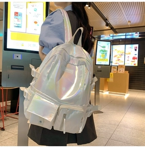 Detail of holographic iridescent backpack showing colorful metallic reflection and pockets