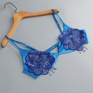 Gros plan sur le soutien-gorge en satin bleu marine avec broderie florale et pompons