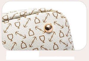 Detail of lychee textured cream tote bag with brown nautical equestrian print and gold stud