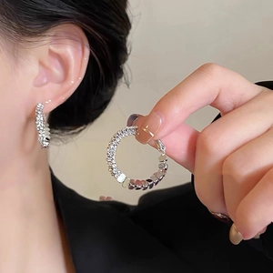 Close-up of silver hoop earrings with a unique textured grain finish on a model