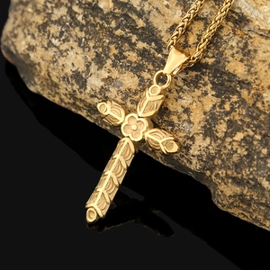 Détail macro du pendentif croix dorée avec motifs floraux sur une pierre naturelle