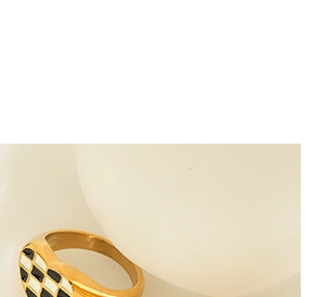 Detailed view of a gold heart ring featuring a black and white checkerboard enamel pattern