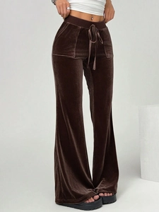 Detail of dark brown velvet flared trousers showing drawstring waist and premium texture