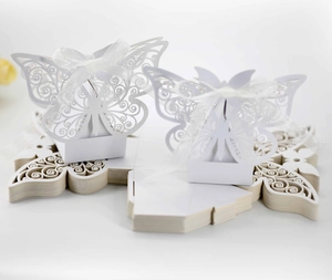 Macro view of white laser-cut butterfly candy boxes with ribbon on flat paper cards