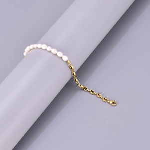 Macro detail of freshwater pearls and golden metal chain necklace on display stand