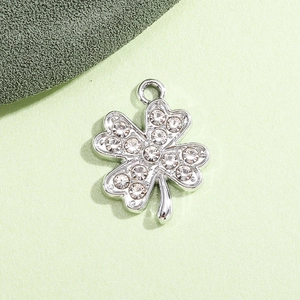 Macro shot of silver four-leaf clover pendant with sparkling rhinestones and metal loop