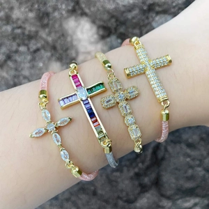 Pulseras minimalistas de cruz dorada con circonitas y cuerdas trenzadas sobre roca natural
