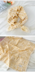 Detail of yellow cotton linen scarf with white geometric prints and delicate lace trim