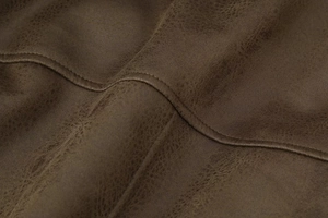 Detailed macro view of brown faux suede fabric texture and fine stitching on the jacket