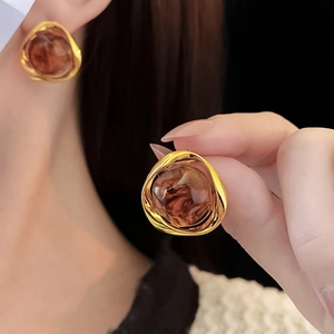 Close-up of geometric amber resin earrings with irregular gold metallic frame