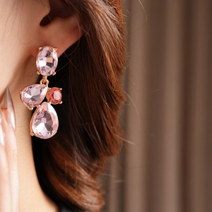 Close-up of vintage geometric teardrop earrings with pink and red gemstones on model