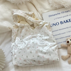 Close-up of white silk tote bag featuring pink bear prints and a brand label detail
