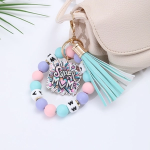 Detail of Super Mom silicone bead keychain with leather tassel on a beige bag handle