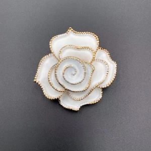 Elegant white camellia flower brooch with gold beaded edges on a sleek black background