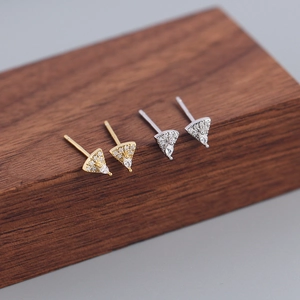 Macro detail of gold and silver S925 sterling silver triangular stud earrings with zircons