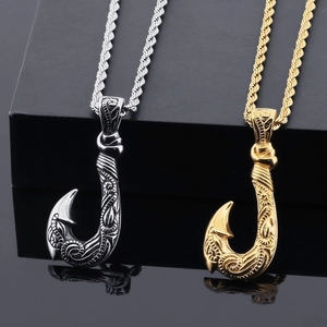 Detailed close-up of silver and gold fish hook pendants with tribal patterns on black base