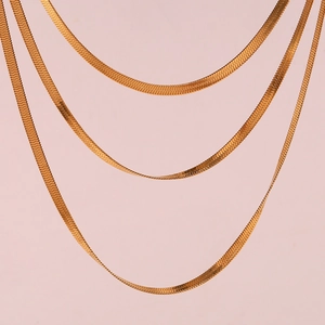 Detailed view of flat snake bone chain in gold finish with polished metallic luster