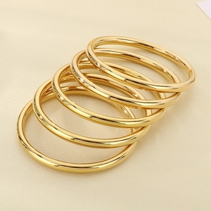 Close-up of five stacked 18k gold plated minimalist 6mm hollow stainless steel bangles