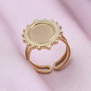 Detail shot of a golden sunflower ring with a round base on pink silk fabric background