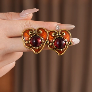 Macro shot of vintage resin heart earring with orange enamel and red cabochon stone