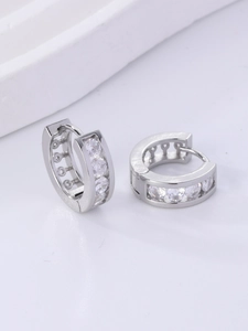 Macro detail of silver-toned huggie hoop earrings with channel-set zircon row