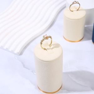 Golden rings with pink gemstone and zircons on a white velvet jewelry display stand