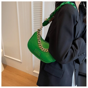 Detail view of a bright green chic shoulder bag with gold chain and woven strap