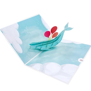 Detail of 3D pop-up birthday card with a blue whale carrying red balloons on the ocean