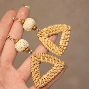 Detail of bohemian triangle woven rattan earrings with white beads and wood accents
