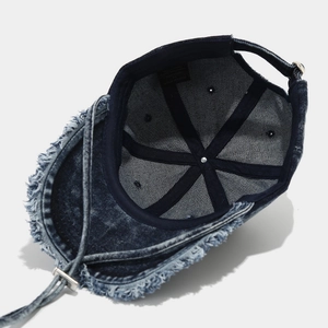 Dettaglio dell'interno del cappellino in denim blu scuro con bordi sfrangiati e etichette