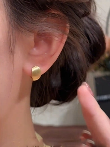 Macro detail of 18k gold plated oval hoop earring with brushed metal finish