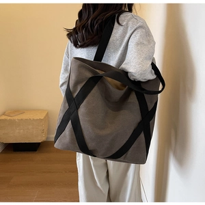 Detail of taupe canvas tote bag with black cross-stitched wide straps for durability