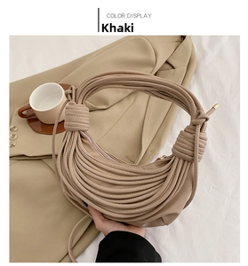Detail of khaki knot shoulder bag with woven strap design against a lifestyle background