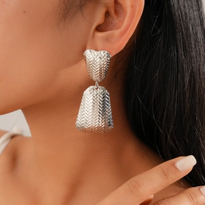 Close-up of silver long geometric earrings with textured woven pattern on a model