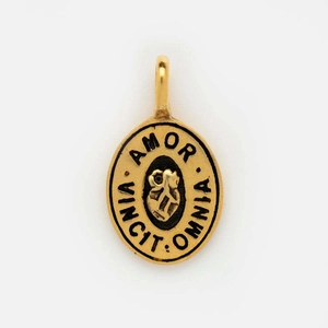 Detailed close-up of golden oval pendant with Amor Vincit Omnia engraving and heart motif