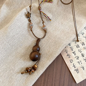 Close-up of wooden gourd pendant necklace with braided rope and ethnic star beads